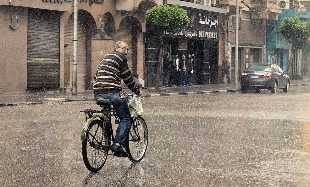 A man in Cairo riding his bike under heavy rain - Wikimedia/Mohamed Hozyen