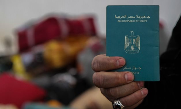 FILE - A man holds his Egyptian passport