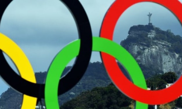 © AFP/File | The Christ the Redeemer statue is seen through a set of Olympic rings in Rio de Janeiro