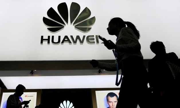 People walk past a sign board of Huawei at CES Asia 2016 in Shanghai – Reuters 