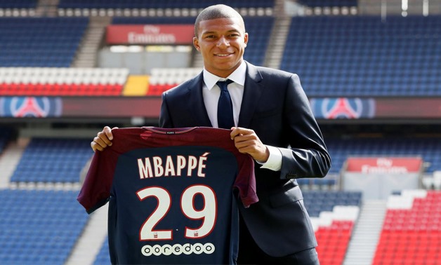 New Paris St-Germain player Kylian Mbappe poses with the club shirt after a press conference.  Reuters