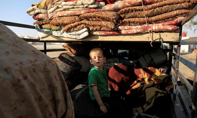 A boy who fled Deir Ezzor sits on a truck with his family belongings at a camp in Ain Issa, north of Raqqa - REUTERS
