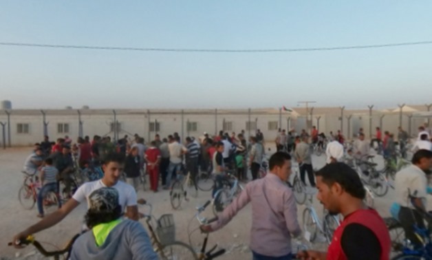 Syrian refugees surround a bike vendor at the edge of the Zaatari camp - REUTERS
