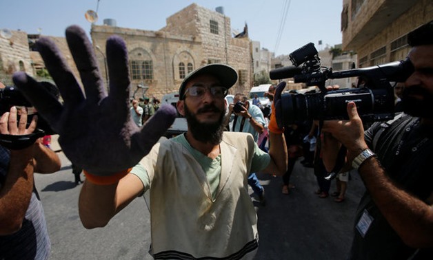An Israeli settler blocks cameras during a protest by Palestinians in the old city of the West Bank city of Hebron - Reuters