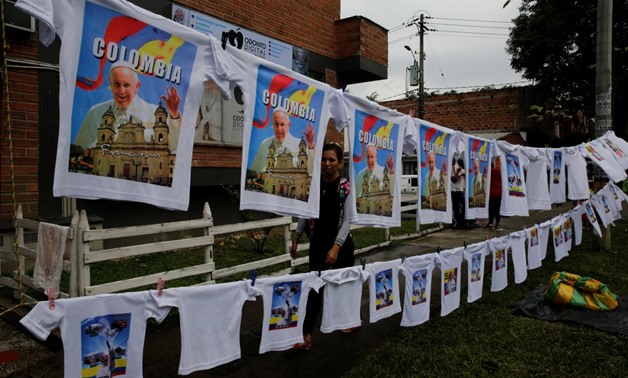 A woman sells t-shirts with images of Pope Francis as the faithful (not pictured) arrive for a holy mass on Saturday by Pope Francis outside Olaya Herrera Airport, Medellin, Colombia September 8, 2017. REUTERS/Henry Romero