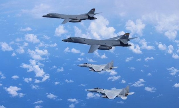 Japan's Self-Defense Forces F-15 fighter jets (bottom) conduct an air exercise with U.S. Air Force B-1B Lancer bombers flying from Andersen Air Force Base, Guam, in the skies above the East China Sea, Japan, in this photo released by the Air Staff Office 