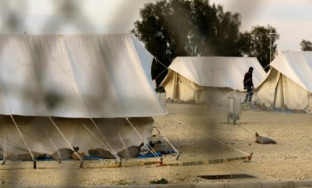 A Syrian refugee walks between tents at a reception centre in Kokkinotrimithia outide the Cypriot capital Nicosia on March 7, 2017
