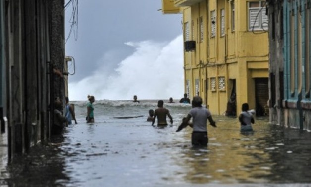 Cubans wade through a flooded street near the Malecon seafront promenade in Havana, on September 10, 2017.