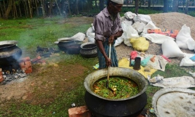 © AFP / by Nick Perry, Sam JAHAN | A man prepares food for Rohingya refugees in the Bangladeshi city of Teknaf