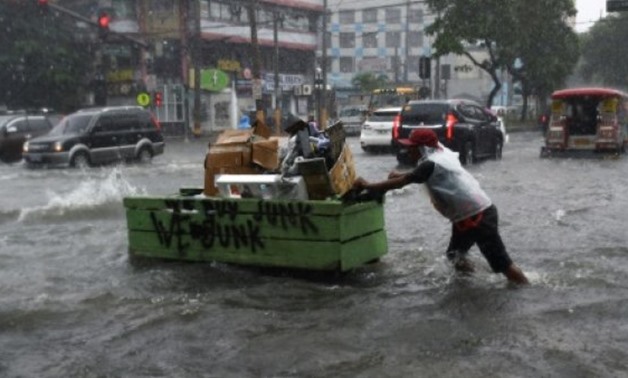 © AFP | A resident pushes his cart as he wades a flooded main street in Manila after a tropical depression locally codenamed "Maring" passed across the main island of Luzon and just beside the Philippine capital