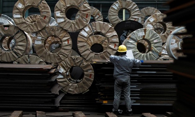FILE PHOTO - A worker checks steel coils and steel sheets at a distribution warehouse in Urayasu, east of Tokyo April 19, 2012. REUTERS/Toru Hanai/File Photo