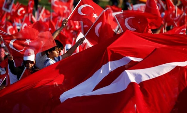 FILE PHOTO: People wave Turkey's national flags as they attend a ceremony marking the first anniversary of the attempted coup at the Bosphorus Bridge in Istanbul, Turkey July 15, 2017. REUTERS/Murad Sezer