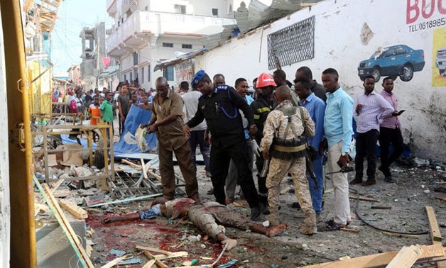 Somali security forces look at the dead body of a man killed after car exploded in Al Mukaram street in Mogadishu - REUTERS