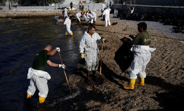 Workers clean a beach covered with oil that leaked from a small oil tanker that sank on September 10 off the shores of Salamina island, at the suburb of Faliro in Athens - REUTERS