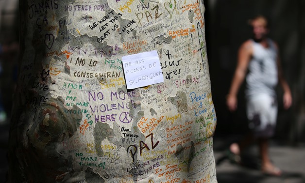 A paper with the sentence "Not to the schengen agreements" written on it is seen on a tree trunk at an impromptu memorial at the site where a van crashed into pedestrians at Las Ramblas in Barcelona, Spain, August 22, 2017. REUTERS/Albert Gea
