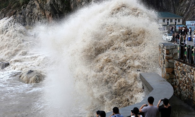 People stand beside a big wave on a waterfront as Typhoon Talim approaches in Wenling, Zhejiang province, China September 14, 2017. Picture taken September 14, 2017. REUTERS/Stringer