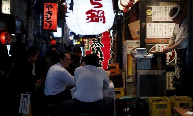 People sit on stools outside a Japanese pub-style restaurant at a business district - Reuters