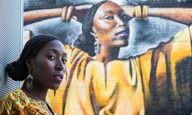 Shaney Blackman stands in the foreground of her striking portrait painted by street artist "Dreph" in London on 25 Aug 2017. Thomson Reuters Foundation/Claudio Accheri