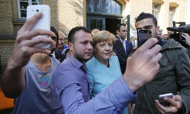 migrants from Syria and Iraq taking selfies with German Chancellor Angela Merkel outside a refugee camp near the Federal Office for Migration and Refugees after their registration at Berlin's Spandau district, Germany  - REUTERS