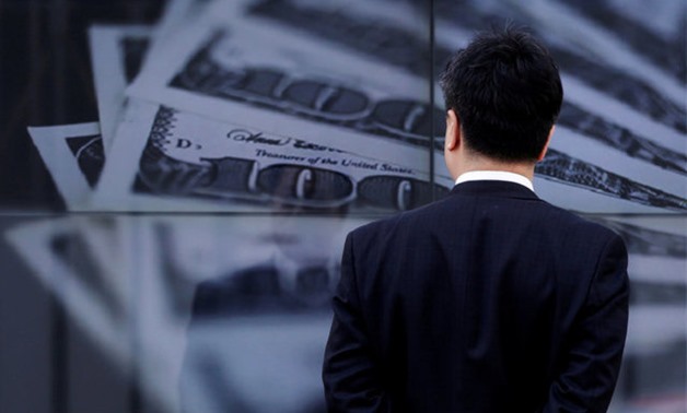 FILE PHOTO: A businessman looks at a screen displaying a photo of U.S. 100 dollar bank notes in Tokyo April 8, 2013. REUTERS/Toru Hanai/File Photo GLOBAL BUSINESS WEEK AHEAD SEARCH GLOBAL BUSINESS 18 SEP FOR ALL IMAGES