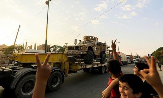 Children flash victory signs as a convoy carrying US-made Oshkosh armoured vehicles heads to the Syrian city of Raqa on September 19, 2017 to reinforce fighters of the Syrian Democratic Forces battling the Islamic State group in its onetime bastion-AFP