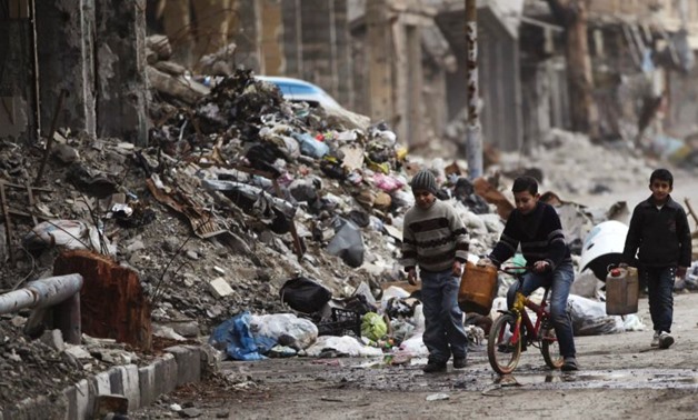 Boys walk along a street covered with garbage and rubble in Deir al-Zor - REUTERS
