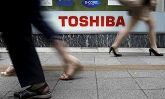 Pedestrians walk past a logo of Toshiba Corp outside an electronics retailer in Tokyo September 14, 2015. REUTERS/Toru Hanai/File Photo