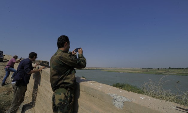 A Syrian army soldier takes a picture of the Euphrates river in al-Bugilia, north of Deir al-Zor, Syria September 21, 2017. REUTERS/Omar Sanadiki