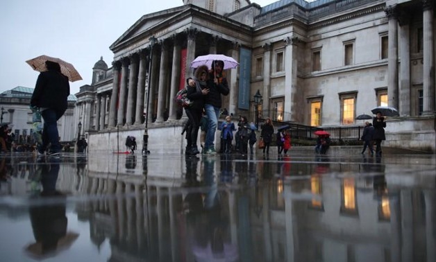 FILE PHOTO: People shelter under umbrellas as the pass the National Gallery on a rainy day in London, Britain January 02, 2016. REUTERS/Neil Hall