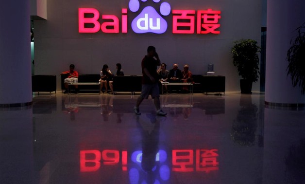 FILE PHOTO: A employee uses his mobile phone as he walks past the company logo of Baidu at its headquarters in Beijing, August 5, 2010. REUTERS/Barry Huang/File Photo