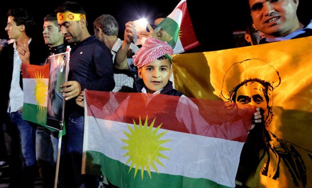 Supporters of Kurdish peshmerga forces hold Kurdish flags as they wait for the troops to cross the Iraqi - AFP
