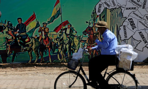 A man rides a bike near a mural supporting the referendum for independence of Kurdistan in Erbil, Iraq September 24, 2017. REUTERS/Alaa Al-Marjani TPX IMAGES OF THE DAY