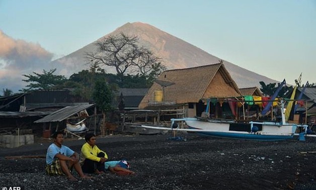 Locals sit near huts and fishing boats on Amed beach, one of the tourist resorts nearest to the Mount Agung volcano, on the island of Bali -AFP