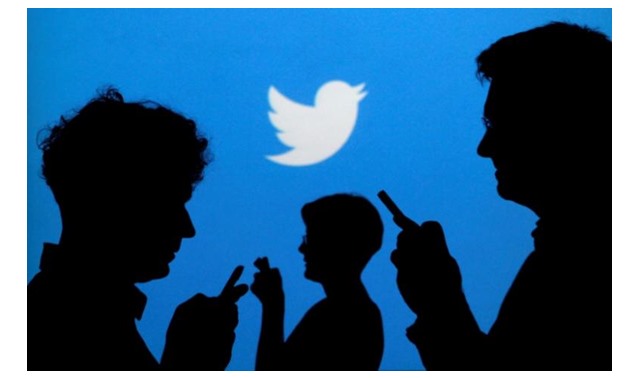  People holding mobile phones are silhouetted against a backdrop projected with the Twitter logo in this illustration picture taken September 27, 2013. REUTERS/Kacper Pempel/Illustration/File Photo