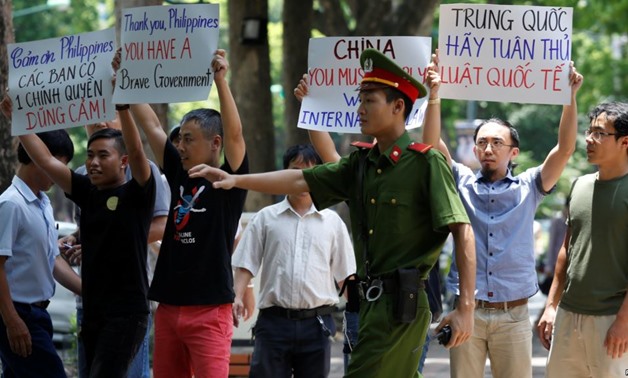 A policeman tries to stop anti-China protesters holding placards during a demonstration in front of the Philippines embassy in Hanoi, Vietnam, July 17, 2016 - REUTERS