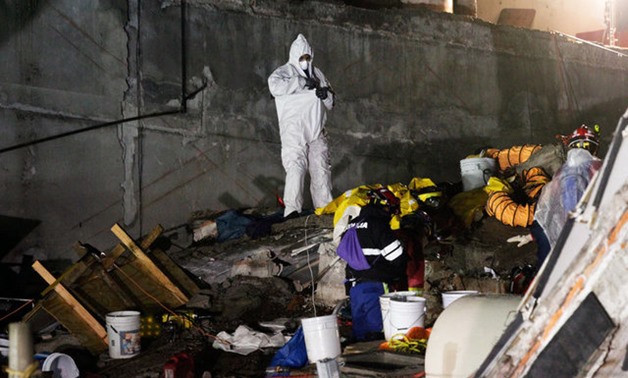 A man puts on a hazmat suit as rescue teams are recovering dead bodies from the rubble of a collapsed building, after an earthquake in Mexico City - REUTERS