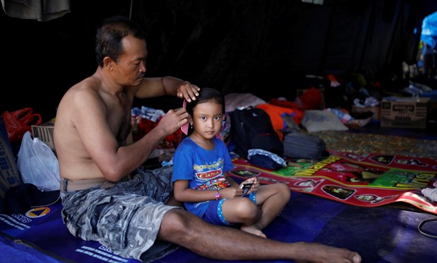 A man combs his daughter's hair inside a tent at a temporary evacuation center for people living near Mount Agung, a volcano on the highest alert level, in Manggis, on the resort island of Bali, Indonesia, September 28, 2017. REUTERS/Darren Whiteside