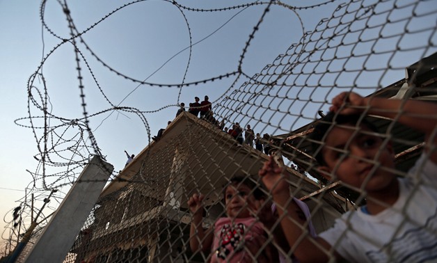 Palestinian children stand behind a fence as people wait for the return of their relatives from the annual Haj pilgrimage in Mecca, at Rafah border crossing in the southern Gaza Strip September 12, 2017. REUTERS/Ibraheem Abu Mustafa