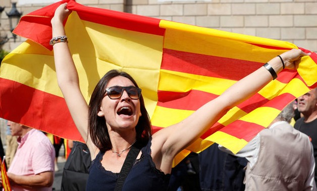A woman holds up a joint Catalan and Spanish flag joined together during a demonstration in favor of a unified Spain a day before the banned October 1 independence referendum, in Barcelona, Spain, September 30, 2017. REUTERS/Yves Herman