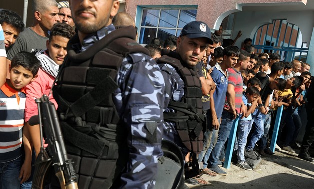 Policemen stand guard as Palestinians wait for the arrival of Palestinian Prime Minister Rami Hamdallah and his government at Erez crossing in the northern Gaza Strip October 2, 2017 - REUTERS