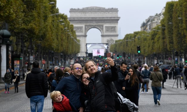 A family posses for a selfie along the Champs-Elysees with the Arc de Triumph as a backdrop during a "car free" day in Paris on October 1, 2017