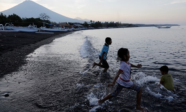 Balinese children play on the beach near Mount Agung, a volcano on the highest alert level, outside the current danger zone in Amed, on the resort island of Bali -  REUTERS/Darren Whiteside