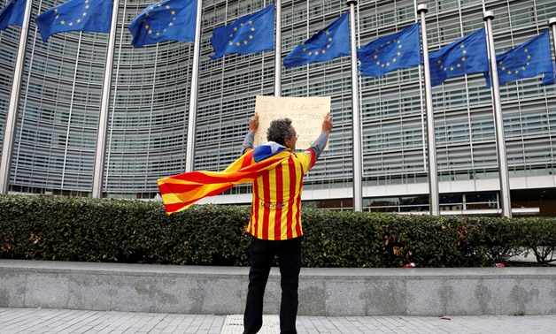 Catalan Raimon Castellvi, wearing a flag with an Estelada (Catalan separatist flag), holds a sign as he protests outside the European Commission in Brussels after Sunday's independence referendum in Catalonia, Belgium October 2, 2017. REUTERS/Francois Len