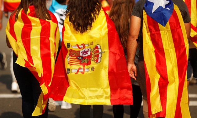 Youths wrapped in a Catalan, a Spanish and an Estelada (Catalan separatist) flag walk through a street during a protest two days after the banned independence referendum in Barcelona, Spain, October 3, 2017. Picture taken October 3, 2017. REUTERS/Jon Nazc