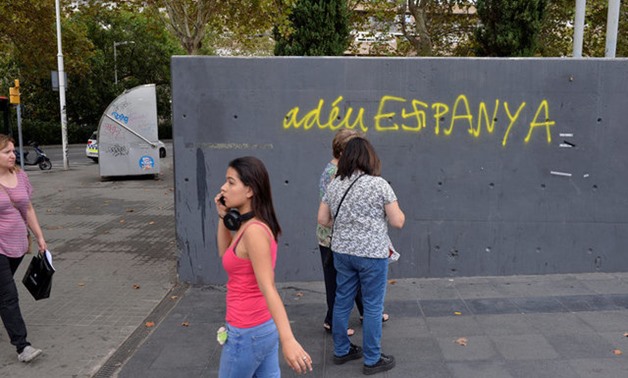 A woman walks past graffiti reading, in Catalan, "Goodbye Spain", in Barcelona, Spain, October 4, 2017. REUTERS