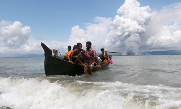 Smoke is seen on Myanmar's side of border as a boat carrying Rohingya refugees arrives to the shore after crossing the Bangladesh-Myanmar border through the Bay of Bengal, in Shah Porir Dwip, Bangladesh, September 11, 2017. Picture taken September 11, 201