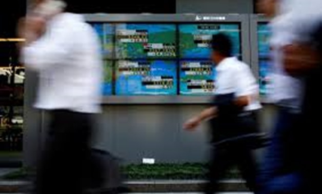 People walk past an electronic board showing Japan's Nikkei average outside a brokerage at a business district in Tokyo, Japan August 9, 2017. REUTERS/Kim Kyung-Hoon
