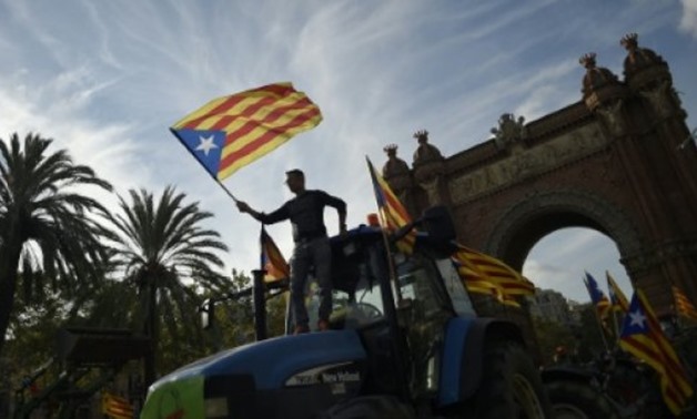 Supporters of Catalan independence wave Catalan flags as they drive with tractors through the Arc de Triomf (Triumphal Arch) in Barcelona on October 10, 2017 - AFP