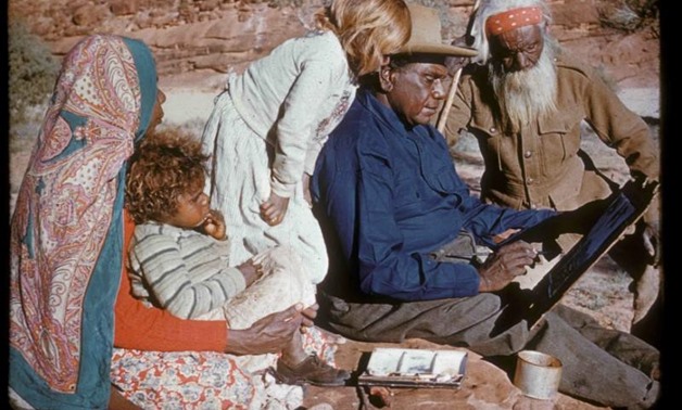 An undated photo released on October 14, 2017 shows family members watching Australia's most famous Aboriginal artist, Albert Namatjira, sitting on a rock as he paints. Pastor S.O. Gross-courtesy of the Strehlow Research Centre/Handout via REUTERS