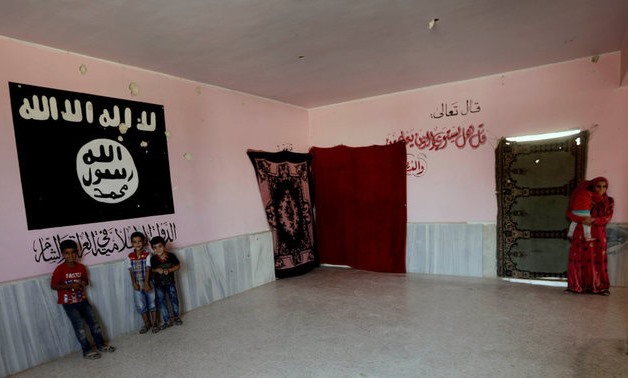 Internally displaced boys who fled Deir al Zor, stand near a wall painting of ISIS flag, at former Islamic State base, in the Syrian city of al-Bab, Syria September 19, 2017. REUTERS/Khalil Ashawi